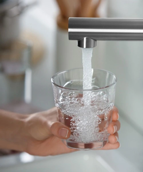 Una persona que llena un vaso de agua de un grifo